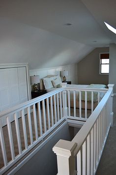 an attic bedroom with white railings and bed in the corner on the second floor