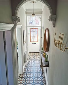 a hallway with blue and white tile flooring next to a doorway that has a mirror on the wall