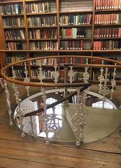 a circular glass table in front of a bookshelf filled with lots of books