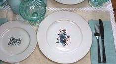 there is a place setting with plates and silverware on the dining table set for two