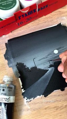 someone is painting the side of a piece of cardboard with black paint and some other things