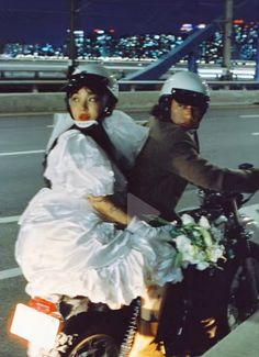 a man and woman riding on the back of a motorcycle