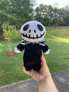 a hand holding a black and white stuffed animal with a jack skellingy face