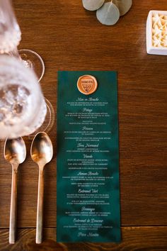 a menu sitting on top of a wooden table next to silverware and spoons