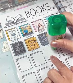 a person is holding a stamper over a book with stickers on it and there are books in the background