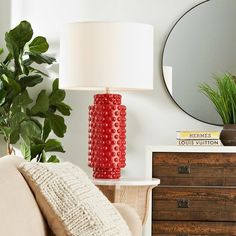 a red lamp sitting on top of a table next to a mirror and wooden dresser