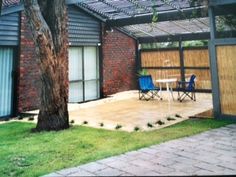 a patio with chairs and a table under a pergolated roof next to a tree