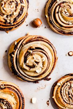 several cinnamon rolls with nuts on top of a baking sheet and one has been cut in half to show the filling