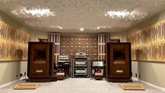 an empty room with speakers in it and lights on the ceiling above them, along with carpeted flooring