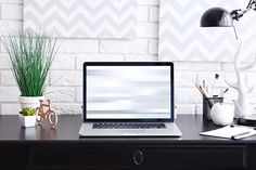 an open laptop computer sitting on top of a desk next to a potted plant