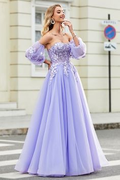 a woman in a purple dress is standing on the street with her hand up to her face