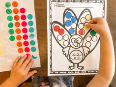 a child's hands holding up a turkey themed coloring book next to a paper bag with colored circles on it