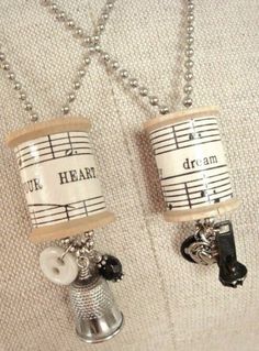 two coffee mugs with musical notes on them are hanging from a silver ball chain