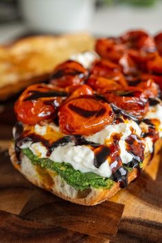 a close up of a sandwich on a cutting board with tomatoes and other toppings