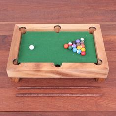 a pool table made out of wood with balls on the top and one ball in the middle