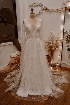 a white wedding dress on display in front of a mirror and other items behind it