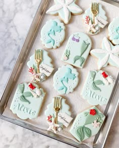 decorated cookies in the shape of mermaids on a tray