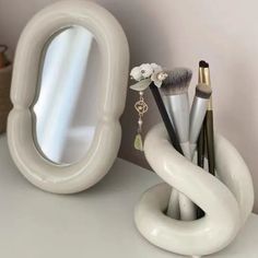 a white vanity mirror sitting on top of a counter next to makeup brushes and other items