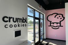 a pink and black wall with the words crumb cookies on it in front of a window