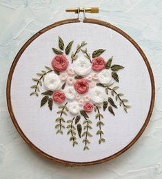 a white and pink flower embroidery on a wooden hoop