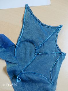 a piece of blue fabric sitting on top of a wooden table next to a pair of scissors