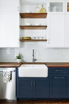 a kitchen with white cabinets and wooden counter tops, an island style sink and dishwasher