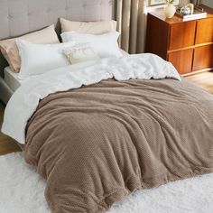 a bed with white and brown blankets on top of it