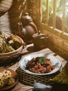 a table topped with plates and bowls filled with food next to potted planters