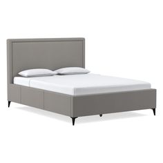 an upholstered bed frame with two pillows