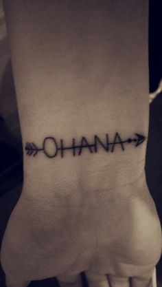 a person's foot with the word ohana on it and an arrow tattoo