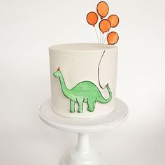 a dinosaur cake with orange balloons on top