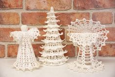 three white crocheted christmas trees with angel figurines next to each other