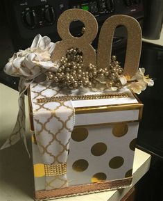 a gift box that has the number 80 on it and is decorated with gold polka dots