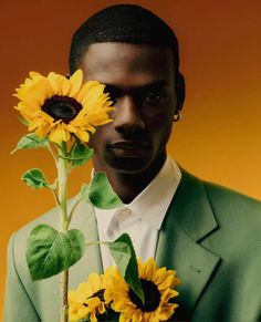 a man in a green suit holding a sunflower