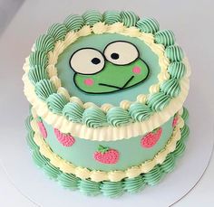 there is a cake that has a face on the top and bottom layer, decorated with green icing