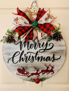 a merry christmas sign hanging on the front door with reindeers and pine cones around it