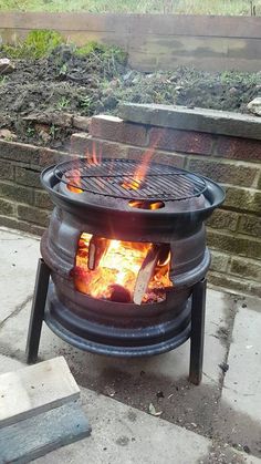 an open fire pit sitting on top of a cement floor next to a brick wall