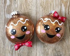 two christmas baubles with faces painted on them, one has a bow and the other has snowflakes