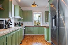 a kitchen with green cabinets and wooden floors