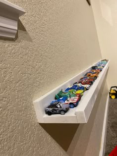 a shelf that has some cars on it and is hanging from the side of a wall