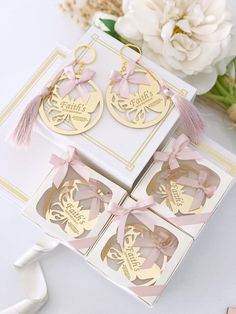 three pairs of earrings with pink ribbon and bow on them sitting in a box next to flowers