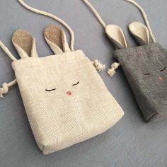 two small bags with bunny ears hanging from the handles, one in grey and one in white