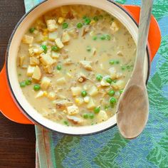 a bowl of soup with peas, potatoes and meat on a colorful napkin next to a wooden spoon