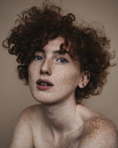 a woman with freckled hair and blue eyes looks off to the side while posing for a portrait