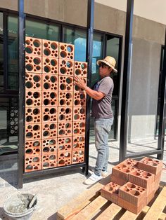 a man standing next to a large stack of bricks on the side of a building