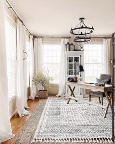 a living room with white curtains and a rug on the floor