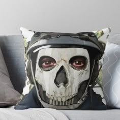 a skull wearing a motorcycle helmet on top of a couch throw pillow with an image of a skeleton in the background