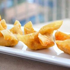 small pieces of food sitting on top of a white plate in front of a window