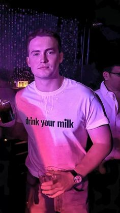 a man holding a wine glass in his right hand and wearing a t - shirt with the words drink your milk on it