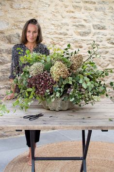 a woman standing next to a table with flowers on it